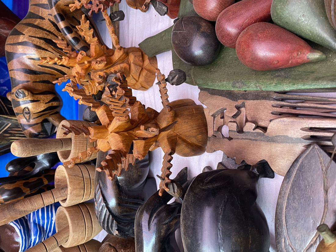 Carved wooden figures, masks and bowls laid out on a market stall