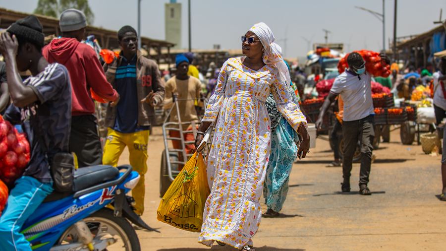 A woman walking through a busy open-air market carrying shopping